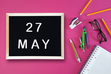 May 27 written in chalk on black board. Calendar date 27th of May on chalkboard on pink blurred...