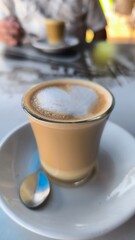 Cup of coffee with saucer, leaning on the bar table, with a man in the background with another cup of coffee.  Meeting at the bar.  Meeting between lovers.  Chat with friends