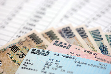 Light blue and red Japan Health Insurance cards on table with japanese yen money close up