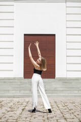 Portrait of a young beautiful blonde model in white trousers