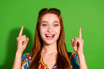 Photo portrait of attractive young woman point up shocked empty space dressed stylish retro clothes isolated on green color background