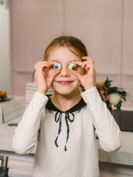 Young girl goofily posing with fake eyeballs, smiling 