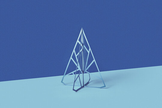 Three dimensional papercraft Christmas tree over blue background.
