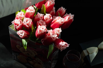 bouquet of beautiful spring flowers, red tulips in paper present bag on black background. Woman day. Flower shop	