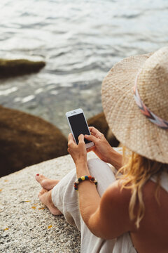 Close up elegant woman typing on her celular near the sea