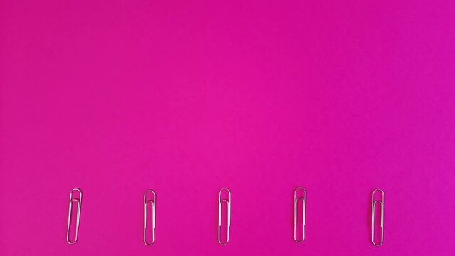 Paper clips move at the bottom of the pink background. Lots of free space for design, inserting text, advertising, messages. Template with the concept of study, paper work, documents.