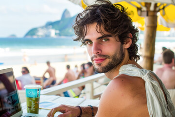 Young man using a laptop on the beach in Rio de Janeiro, Brazil
