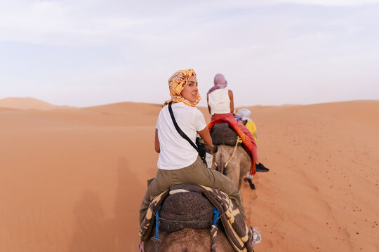 group of people riding camels in the merzouga desert.