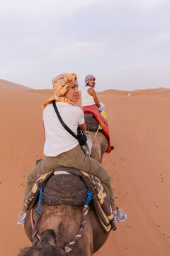 Two women riding a camel in the desert.