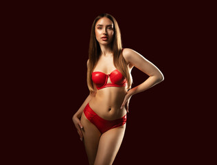 Slender sexy woman in red latex underwear on a red background.