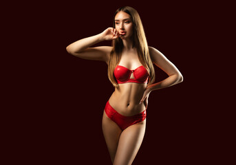 Slender sexy woman in red latex underwear on a red background.