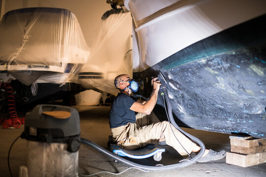Repairman restoring boat hull at nautical workshop