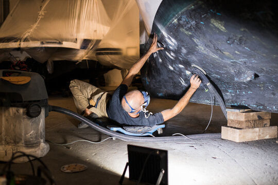 Worker polishing and repairing boat hull