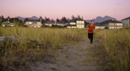child running towards beach through grass trail