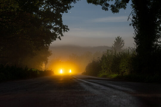 Glowing lights on a misty rural road at night