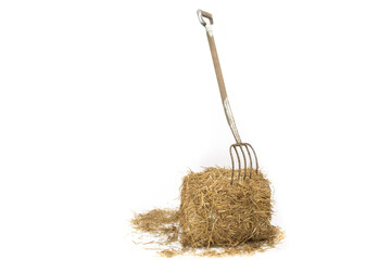 a pitch fork stuck into a bale of straw in a barn