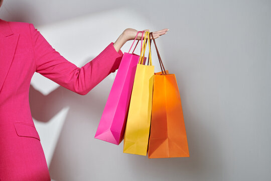 Cropped shot of female hand holding colorful paper shopping bags