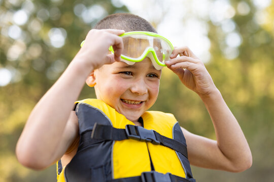 Child, boy smiling with googles and lifejacket for swimming