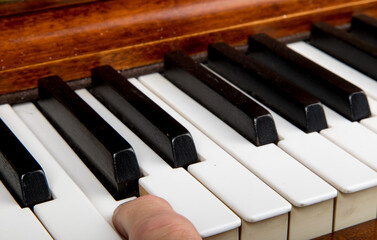 closeup of a male pianist playing the piano with one finger on the white key middle C