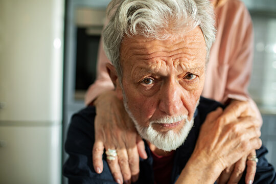 Worried senior couple in kitchen looking at camera