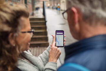 Senior couple using location app on smartphone together in the city