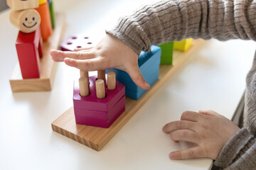 Child playing a fun-filled game of logic with colourful wooden blocks. Game of logic. Educational...