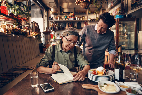 Senior waitress doing expenses at a restaurant table with owner