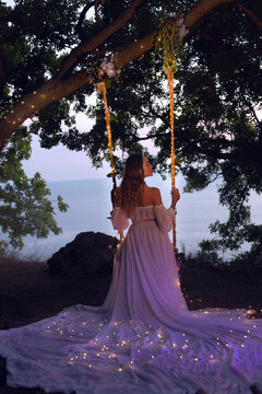 magical photo. girl on a swing in a white dress
