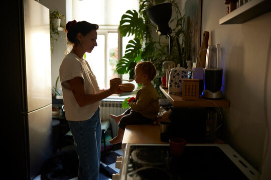 Portrait of a mom feeding her kid at home