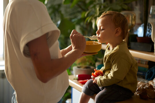 Mother feeds the boy with porridge