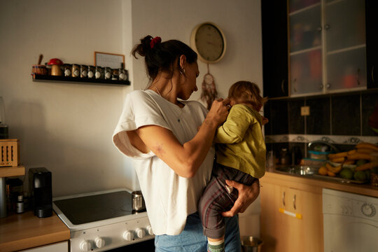 Mother holds a kid in the kitchen