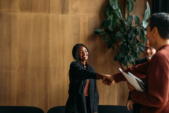 Business people greeting colleague in cafe
