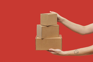 Woman's hands carrying three cardboard boxes in stack