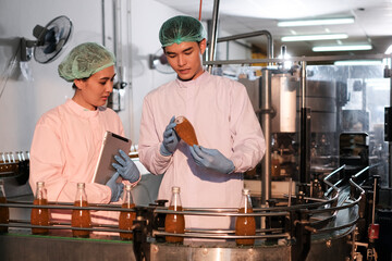 Specialist in factory checking bottles. Two female worker inspecting quality of plastic water tank on conveyor belt in drinking water factory.