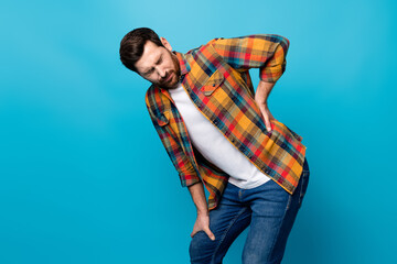 Photo portrait of nice young guy touch back need painkiller wear trendy plaid garment isolated on blue color background - obrazy, fototapety, plakaty