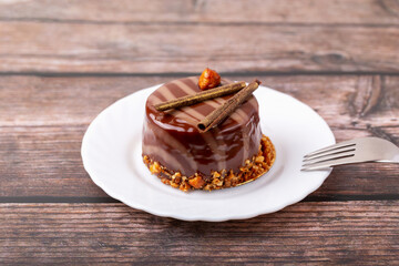 Fresh delicious chocolate cake on plate with fork on wooden background. Caramel glaze and...