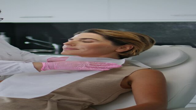 Cosmetologist preparing woman to beauty procedures in modern clinic vertical