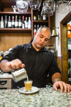 young waiter serving coffee in a bar