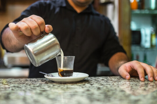 young waiter serving coffee in a bar
