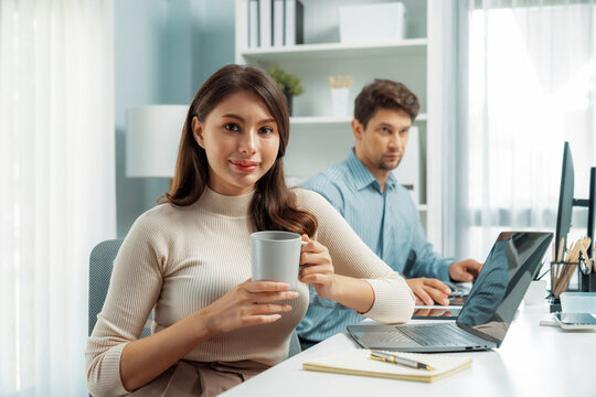 Smiling beautiful woman holding coffee cup to pose for looking at camera photo shooting portrait profile's business, working with smart coworker at modern office at morning on working desk. Postulate.
