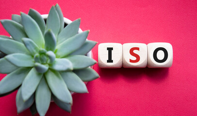 ISO standards quality control symbol. Concept word ISO on wooden cubes. Beautiful red background...
