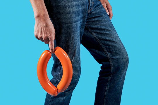 man in jeans holds a pair of plastic casing sausages