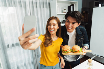 Smiling host chef influencers taking photo with smartphone by selfie together holding double big...