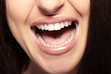 Detailed view of a womans open mouth showing her teeth. Girl talking or screaming or singing.