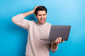Photo of dissatisfied man with stylish haircut dressed beige sweatshirt hold laptop arms on head...
