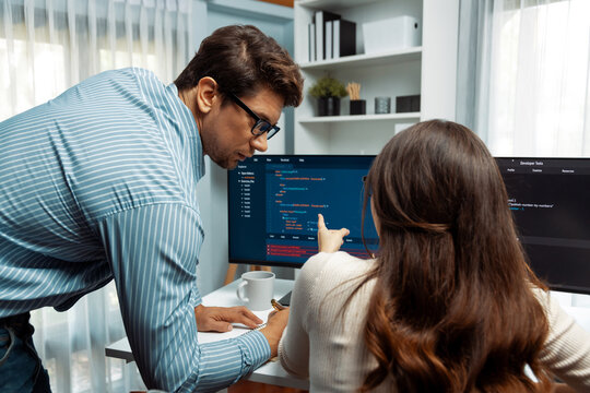 Team skilled developers program coding discussing creative website planning software project on two screen monitor's full stack data analyzing design at office with back side view concept. Postulate.