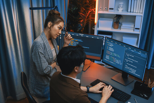 IT developers discussing with point to intelligent website development coder system running data online on pc of two screens with information technology at neon light room at modern office. Infobahn.