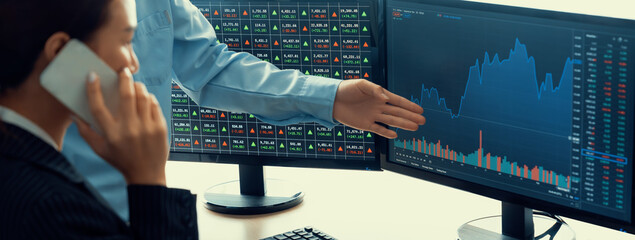 Smart cooperative male trader points the growth analysis stock market graph displayed on computer...