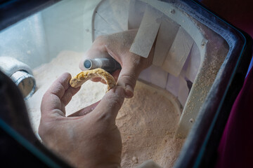 A dental technician seen from above polishes the details of a dental stone model with the handpiece to make it ready to work on. © LaMorenita