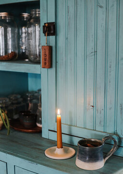 simple lit candle sits on cupboard